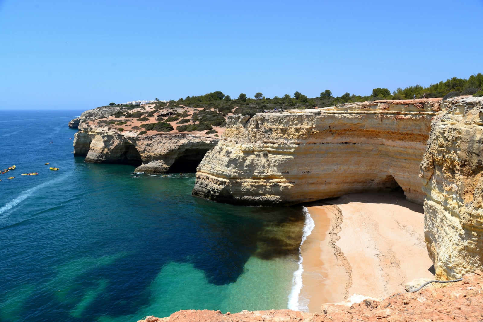 Golden limestone cliffs above a sheltered cove and clear water